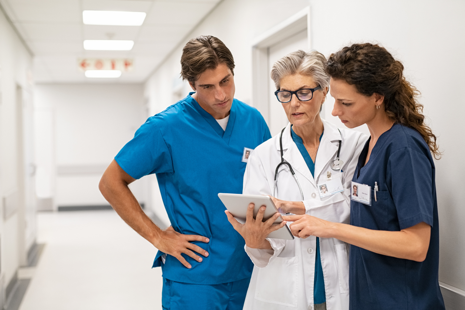 Doctor, physician associate, and nurse read a tablet.